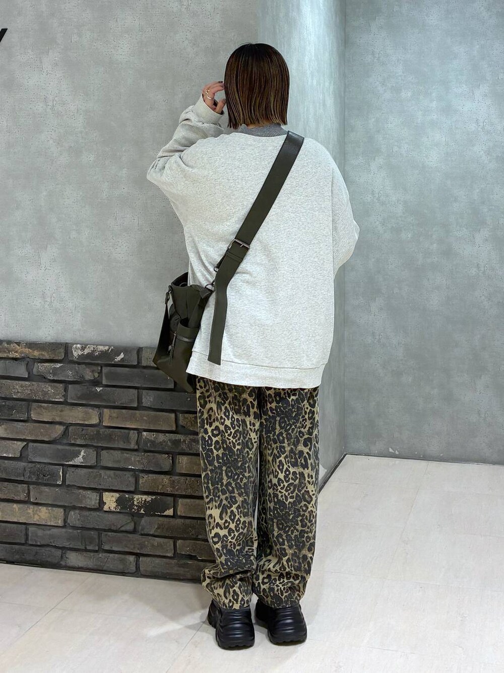 グレー系のスニーカー、グリーン系のボストンバッグ、ベージュ系のスウェットを着用したレディースの冬コーディネートの3枚目の写真