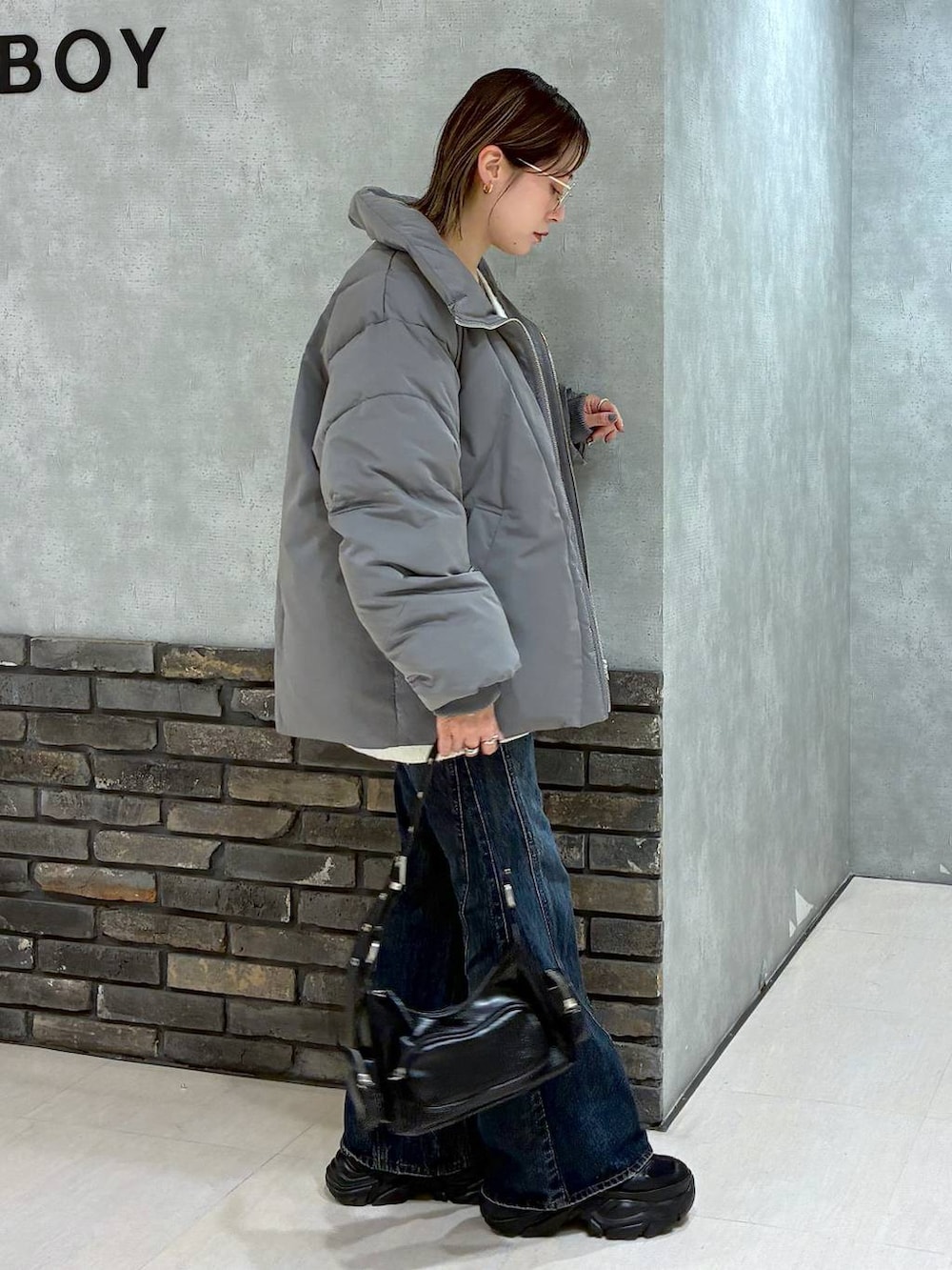 ブラック系のスニーカー、ブルー系のデニムパンツ、グレー系のブルゾンを着用したレディースの冬コーディネートの3枚目の写真