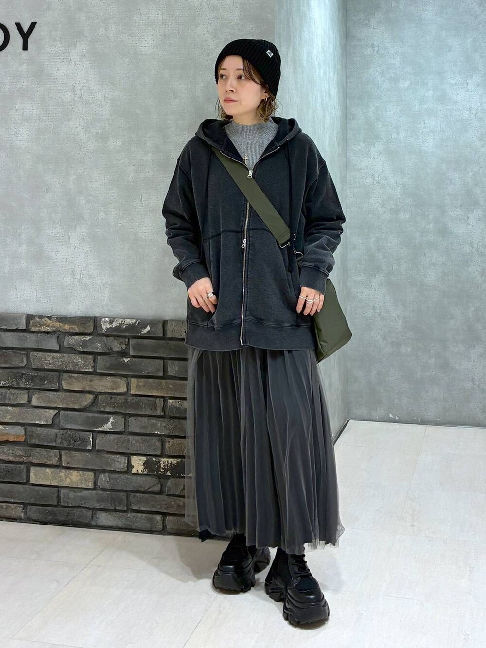 ブラック系のブーツ、グリーン系のボストンバッグ、ブラック系のパーカーを着用したレディースの秋コーディネートの7枚目の写真