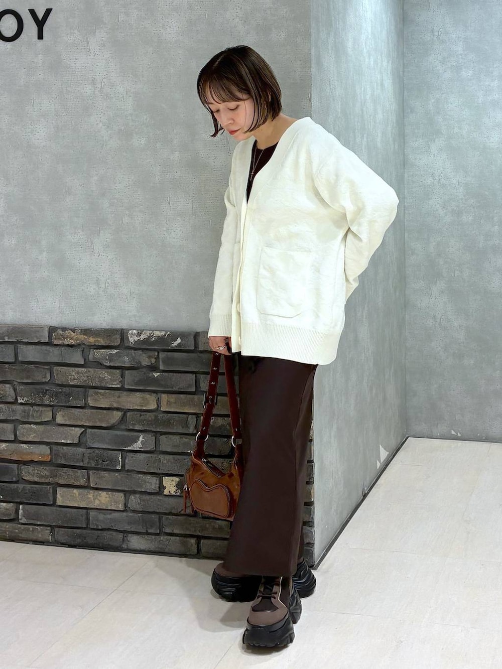 ブラウン系のブーツ、ブラウン系のニット/セーター、ブラウン系のスカートを着用したレディースの冬コーディネートの6枚目の写真