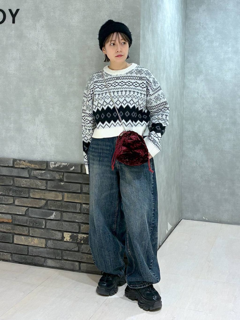 ブラック系のスニーカー、ブルー系のデニムパンツ、レッド系のハンドバッグを着用したレディースの秋コーディネートの5枚目の写真