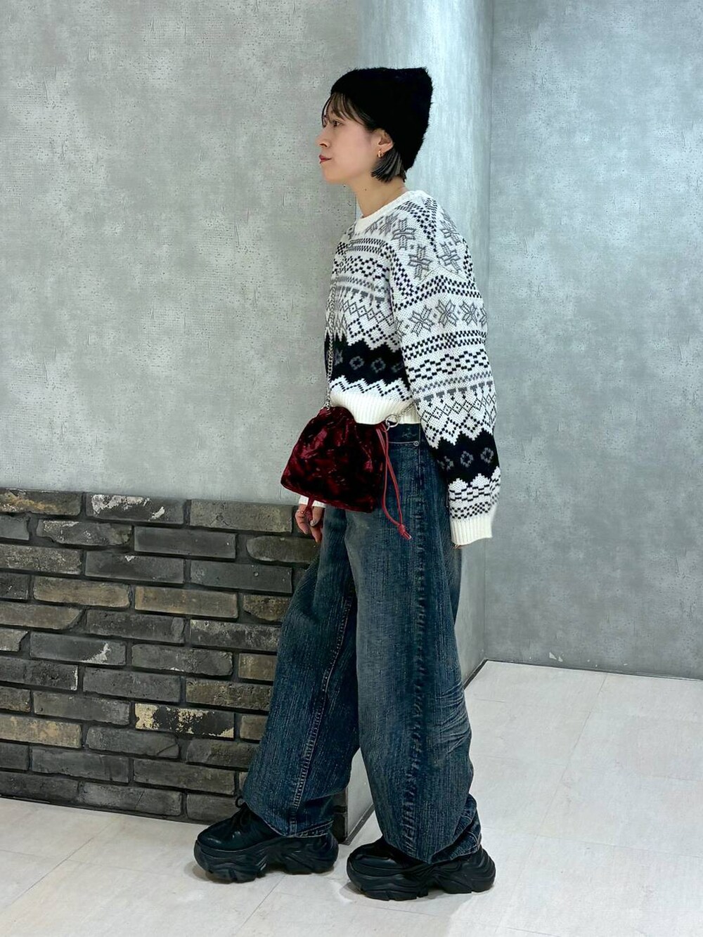 ブラック系のスニーカー、ブルー系のデニムパンツ、レッド系のハンドバッグを着用したレディースの秋コーディネートの4枚目の写真