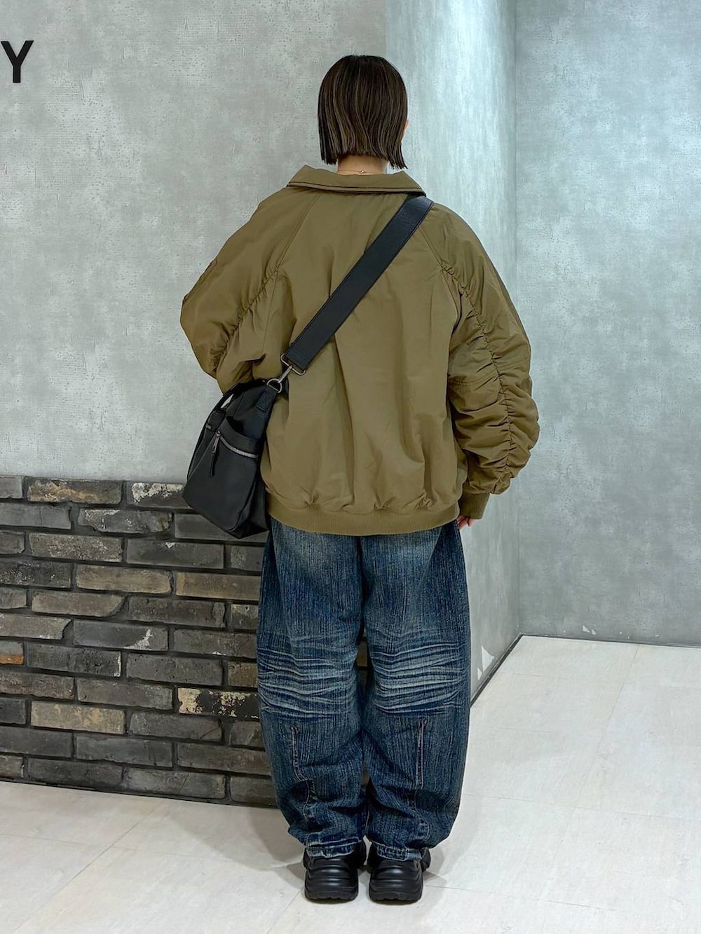 ブラック系のスニーカー、ブラック系のボストンバッグ、ブルー系のデニムパンツを着用したレディースの冬コーディネートの4枚目の写真