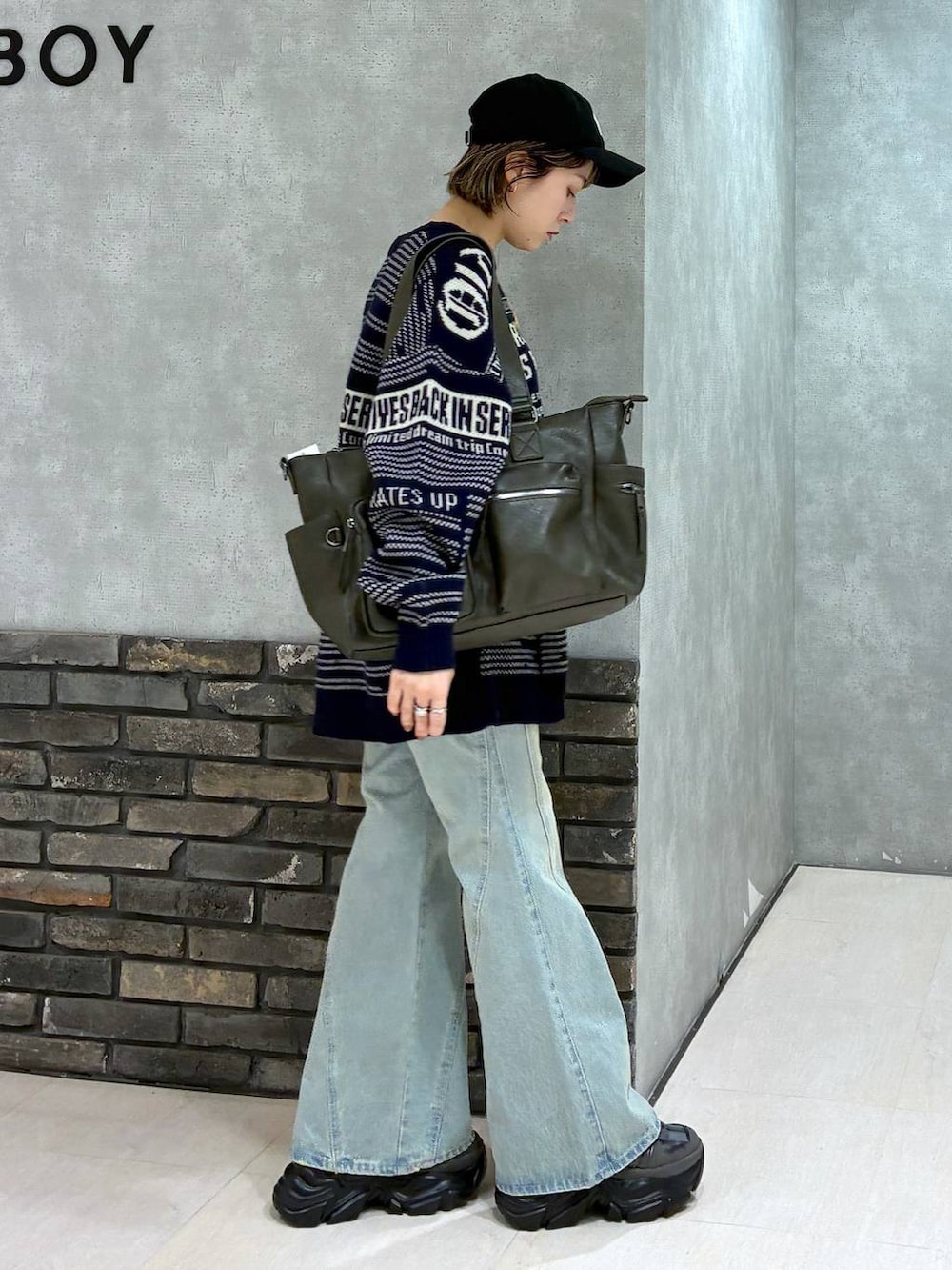 グレー系のスニーカー、ブルー系のデニムパンツ、グリーン系のボストンバッグを着用したレディースの冬コーディネートの2枚目の写真