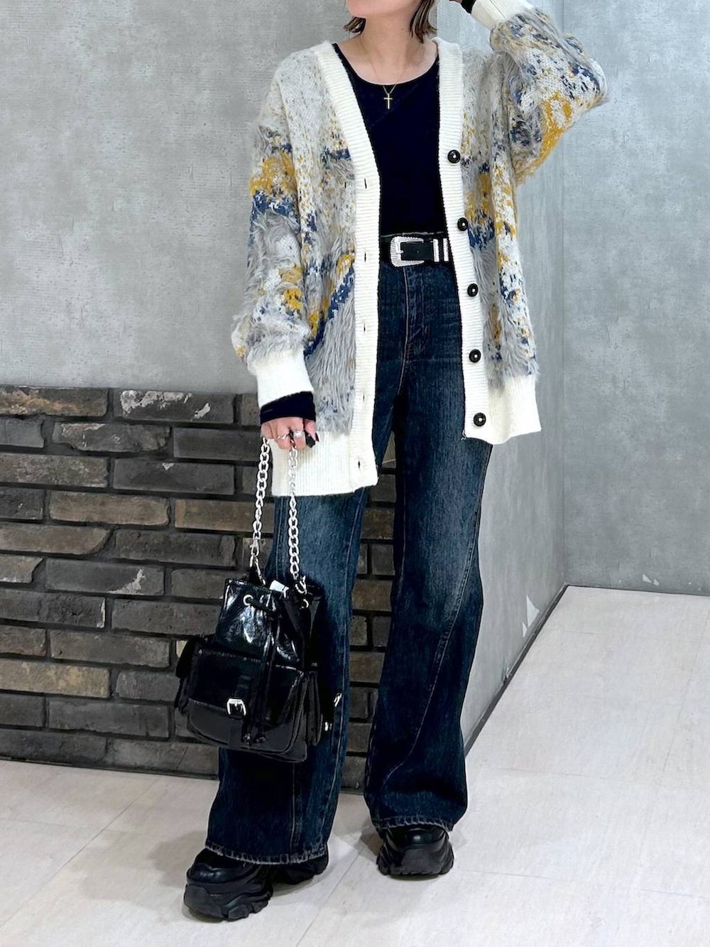 ブラック系のスニーカー、ブルー系のデニムパンツ、ブラック系のショルダーバッグを着用したレディースの秋コーディネートの3枚目の写真