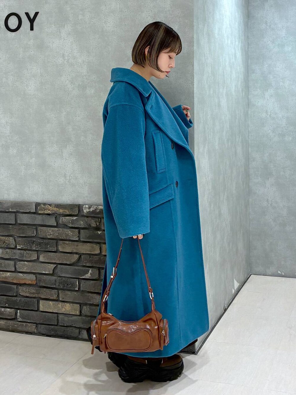 ブラウン系のブーツ、グリーン系のチェスターコート、ブラウン系のニット/セーターを着用したレディースの冬コーディネートの2枚目の写真