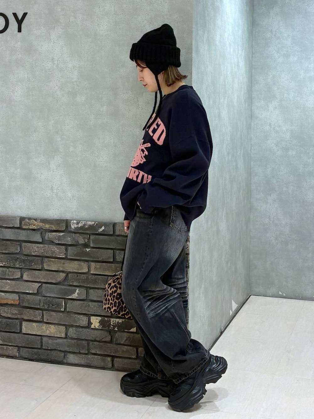 ブラック系のスニーカー、ブルー系のニット/セーター、ブラック系のデニムパンツを着用したレディースの秋コーディネートの5枚目の写真