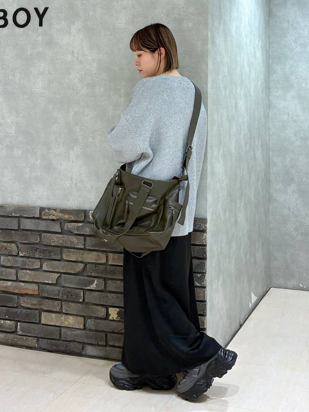 グレー系のスニーカー、グリーン系のボストンバッグ、グレー系のニット/セーターを着用したレディースの冬コーディネートの5枚目の写真