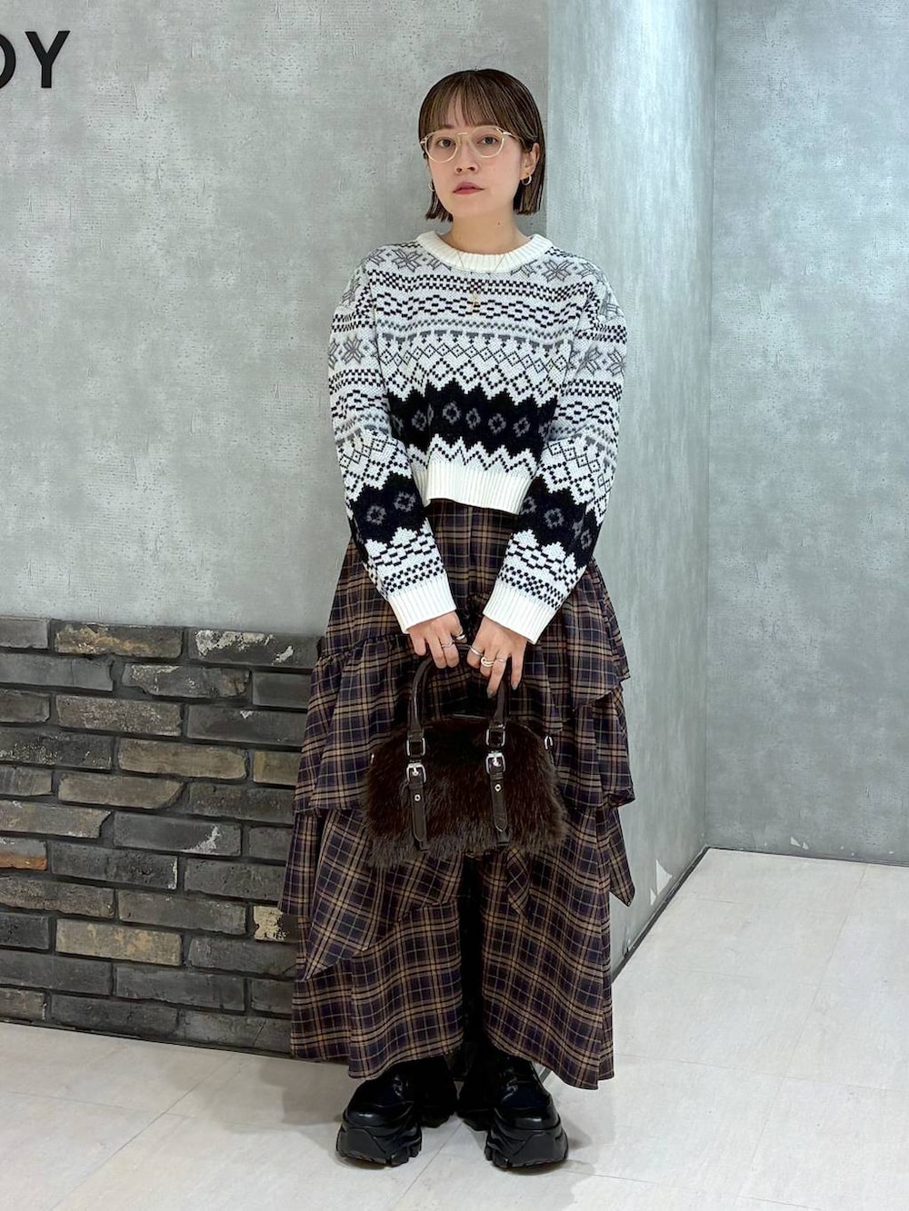 ブラック系のブーツ、ブラウン系のスカート、ブラウン系のボストンバッグを着用したレディースの冬コーディネートの3枚目の写真