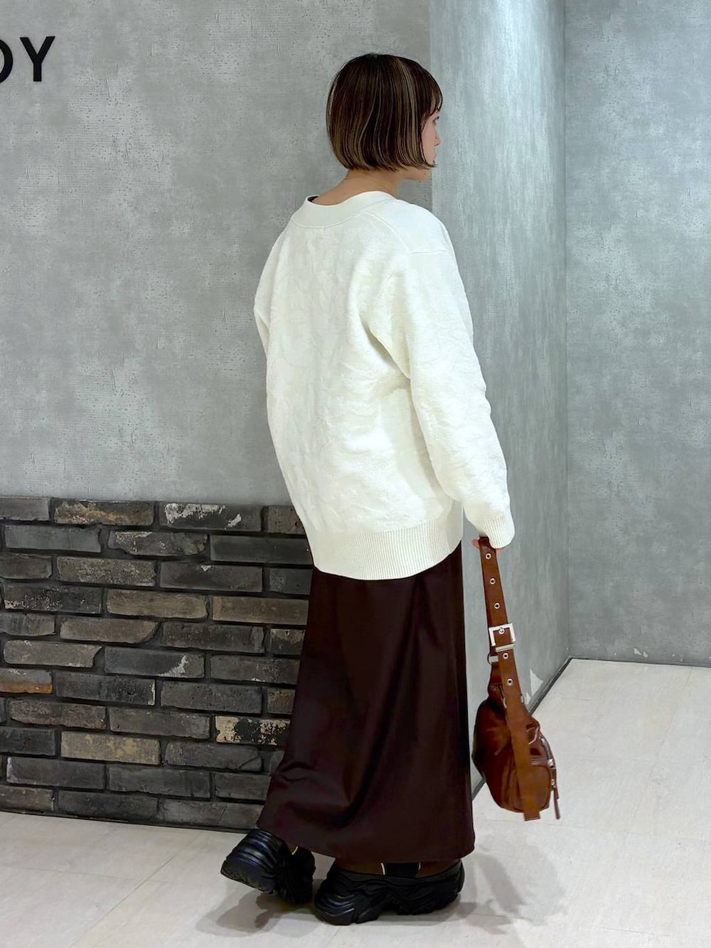 ブラウン系のブーツ、ブラウン系のニット/セーター、ブラウン系のスカートを着用したレディースの冬コーディネートの2枚目の写真