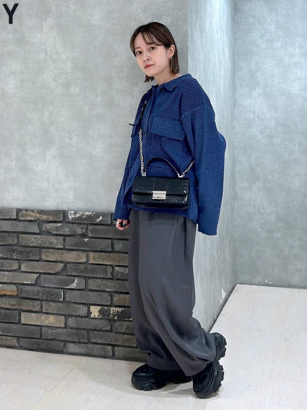 ブラック系のスニーカー、ブラック系のハンドバッグ、ブルー系のブルゾンを着用したレディースの秋コーディネートの4枚目の写真