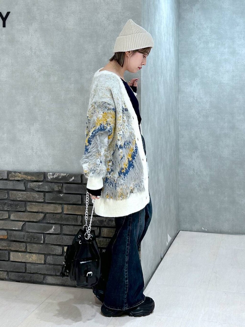 ブラック系のスニーカー、ブルー系のデニムパンツ、ブラック系のショルダーバッグを着用したレディースの秋コーディネートの5枚目の写真