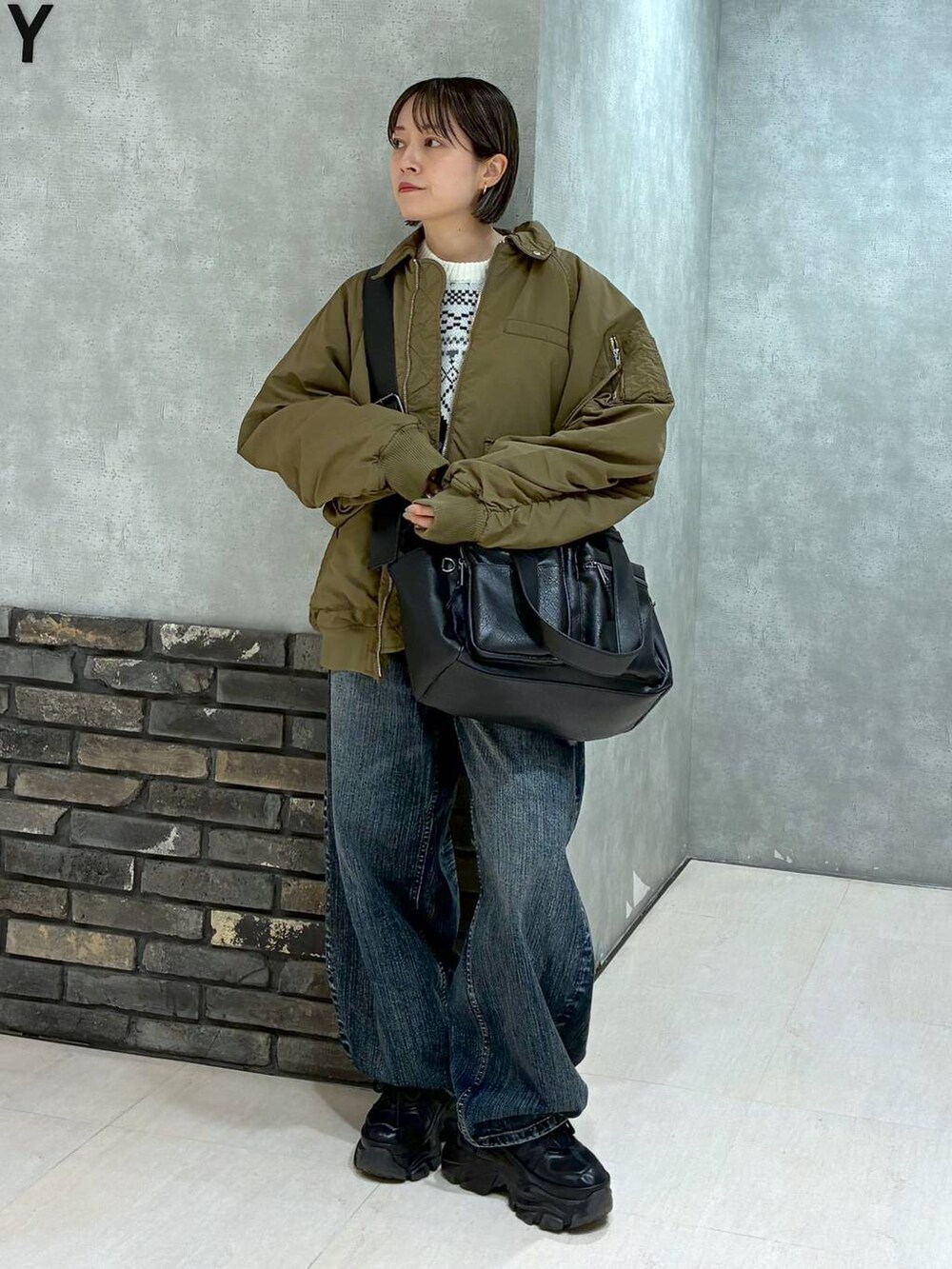 ブラック系のスニーカー、ブラック系のボストンバッグ、ブルー系のデニムパンツを着用したレディースの冬コーディネートの7枚目の写真