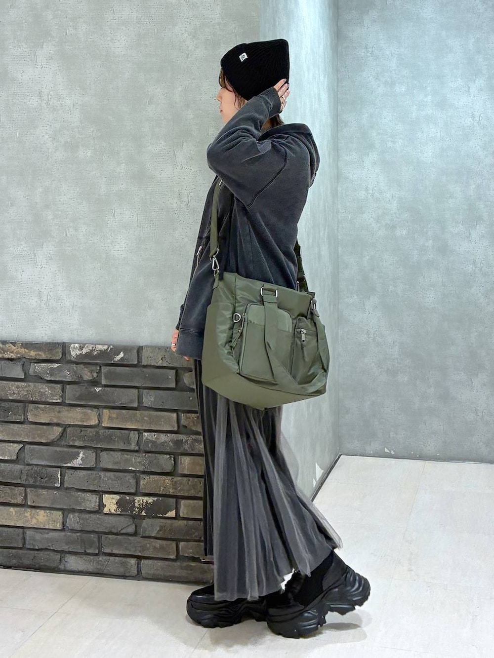 ブラック系のブーツ、グリーン系のボストンバッグ、ブラック系のパーカーを着用したレディースの秋コーディネートの5枚目の写真