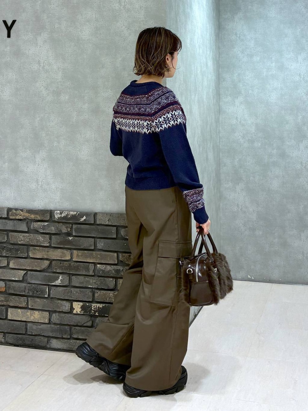 ブラック系のスニーカー、ブラウン系のスラックス、ブラウン系のボストンバッグを着用したレディースの冬コーディネートの2枚目の写真