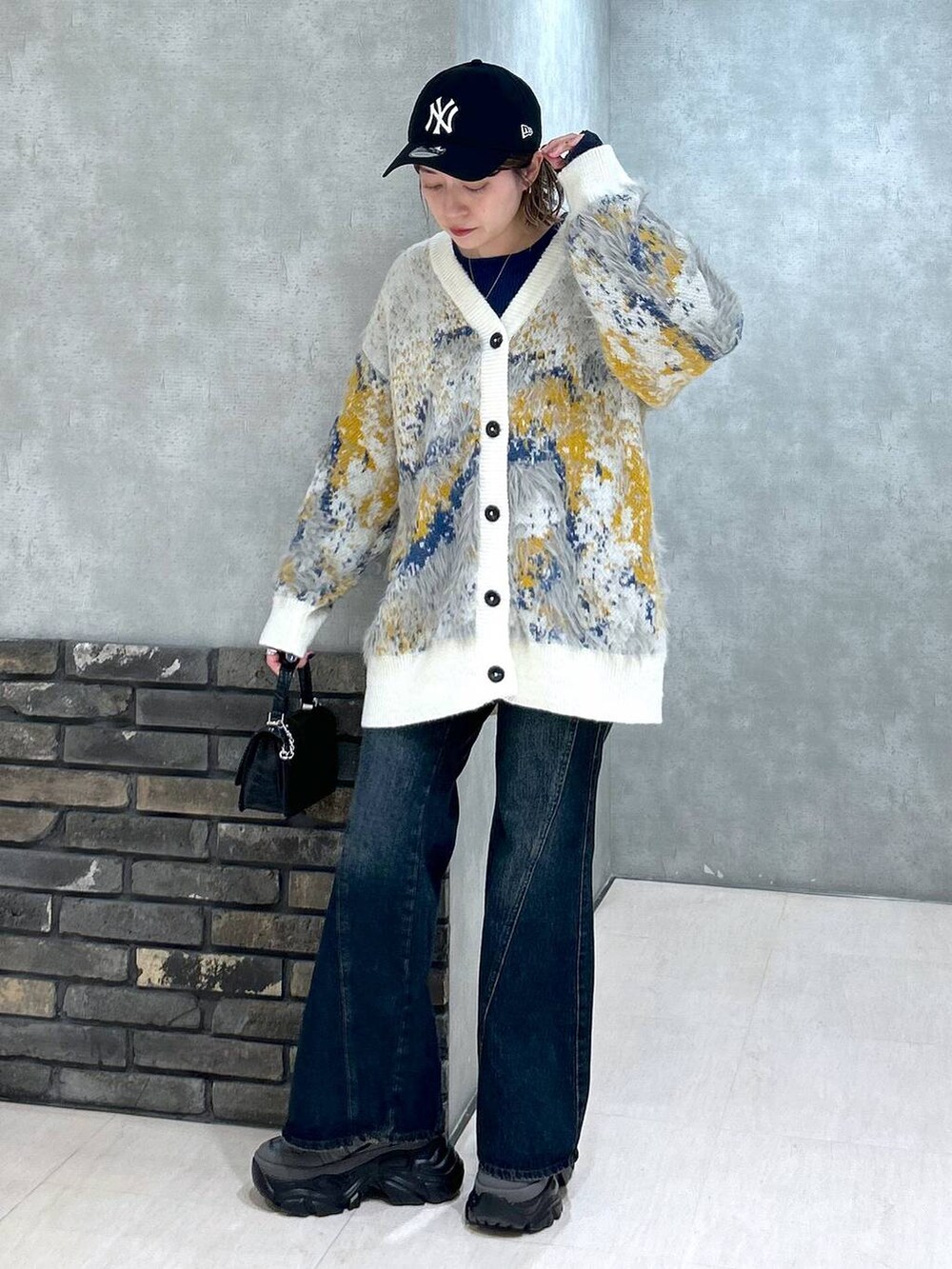 グレー系のスニーカー、ブルー系のデニムパンツ、ブラック系のハンドバッグを着用したレディースの秋コーディネートの8枚目の写真