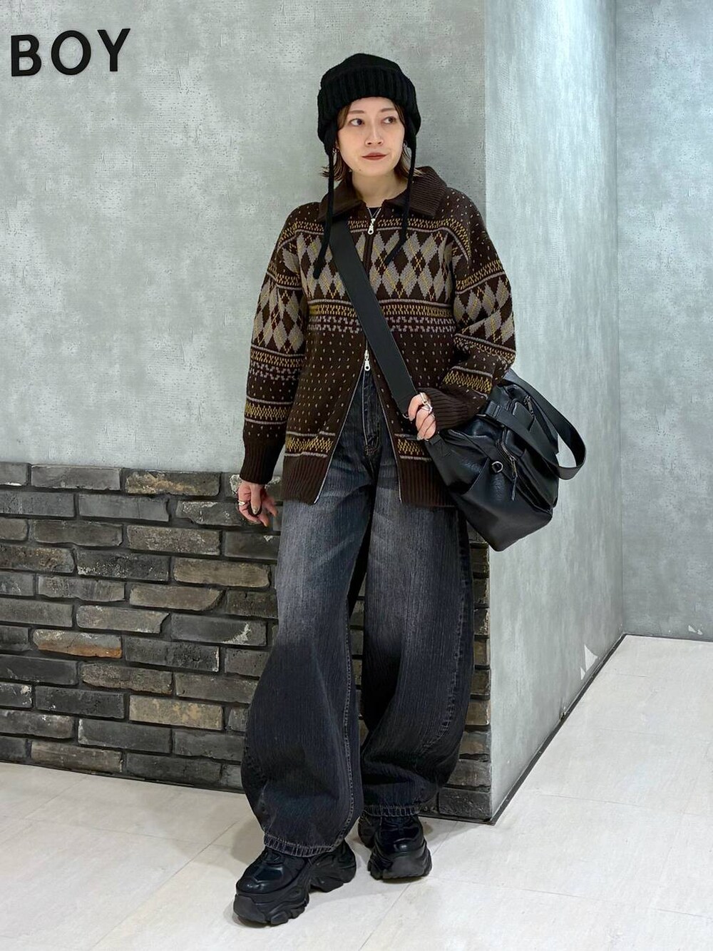 ブラック系のスニーカー、ブラック系のボストンバッグ、ブラック系のデニムパンツを着用したレディースの冬コーディネートの2枚目の写真