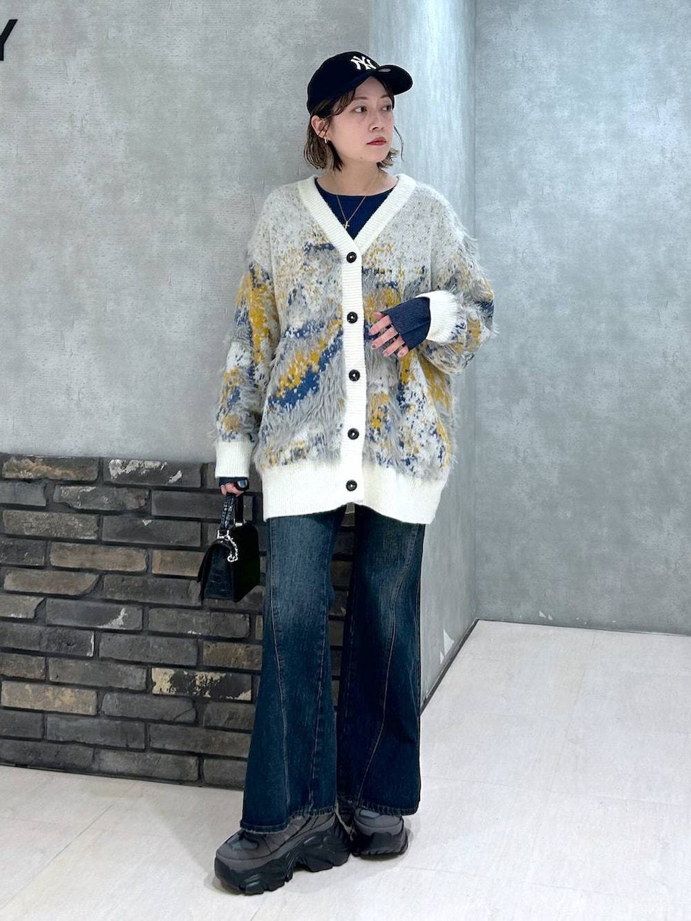 グレー系のスニーカー、ブルー系のデニムパンツ、ブラック系のハンドバッグを着用したレディースの秋コーディネートの9枚目の写真