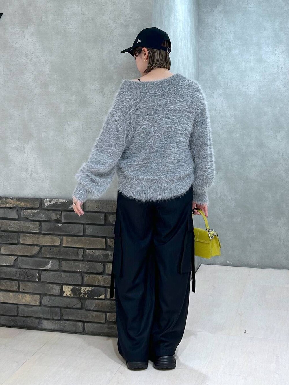 ブラック系のブーツ、イエロー系のハンドバッグ、ブラック系のスラックスを着用したレディースの秋コーディネートの3枚目の写真