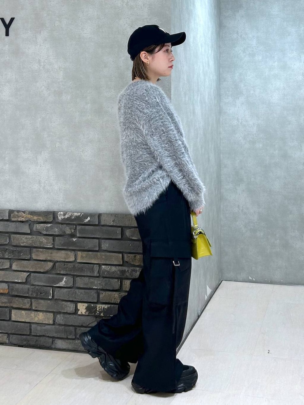 ブラック系のブーツ、イエロー系のハンドバッグ、ブラック系のスラックスを着用したレディースの秋コーディネートの2枚目の写真