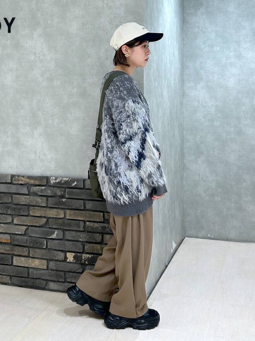 ブラック系のスニーカー、グリーン系のボストンバッグ、グレー系のカーディガン/ボレロを着用したレディースの秋コーディネートの3枚目の写真