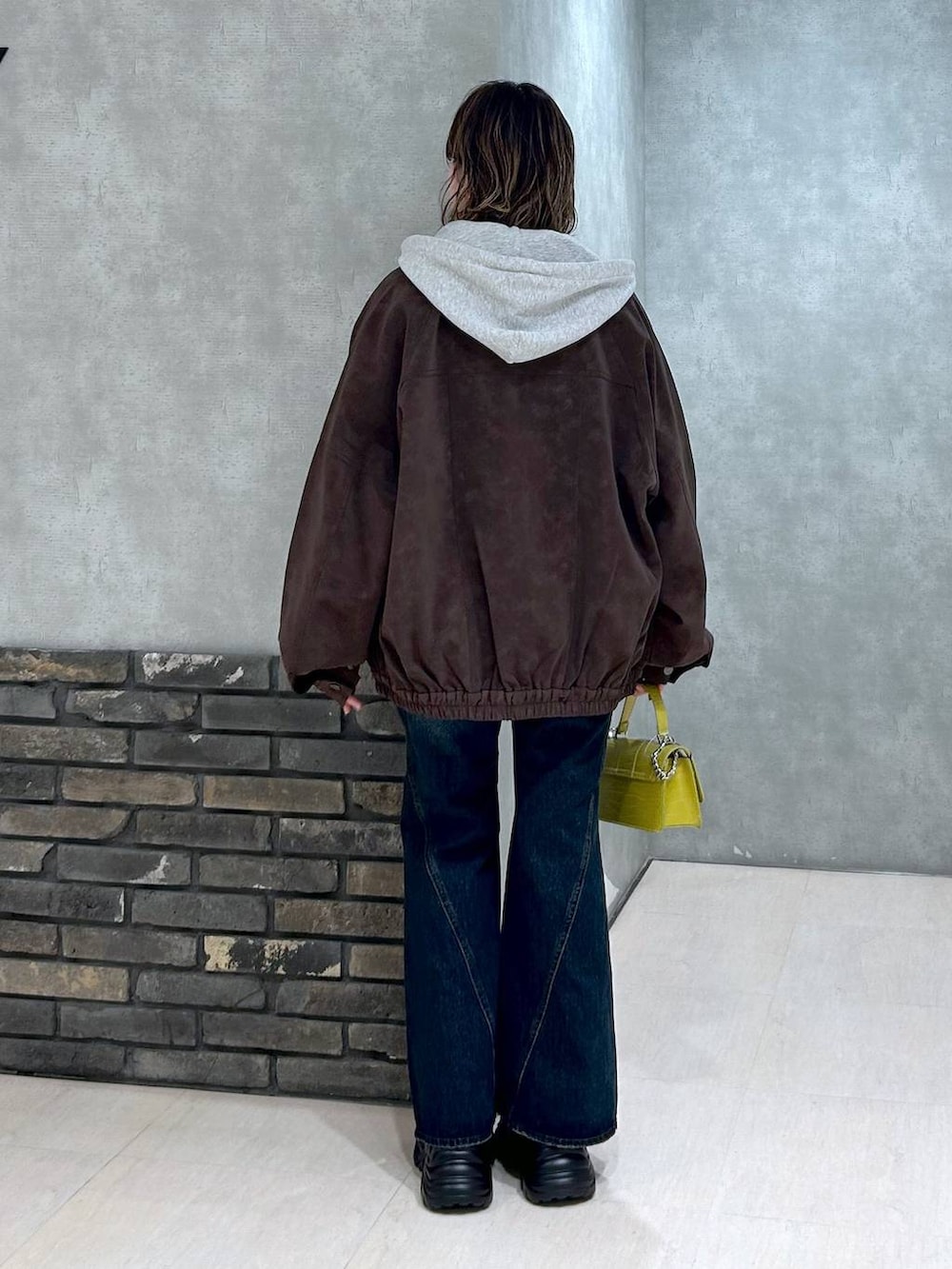 グレー系のスニーカー、ブルー系のデニムパンツ、イエロー系のハンドバッグを着用したレディースの秋コーディネートの4枚目の写真