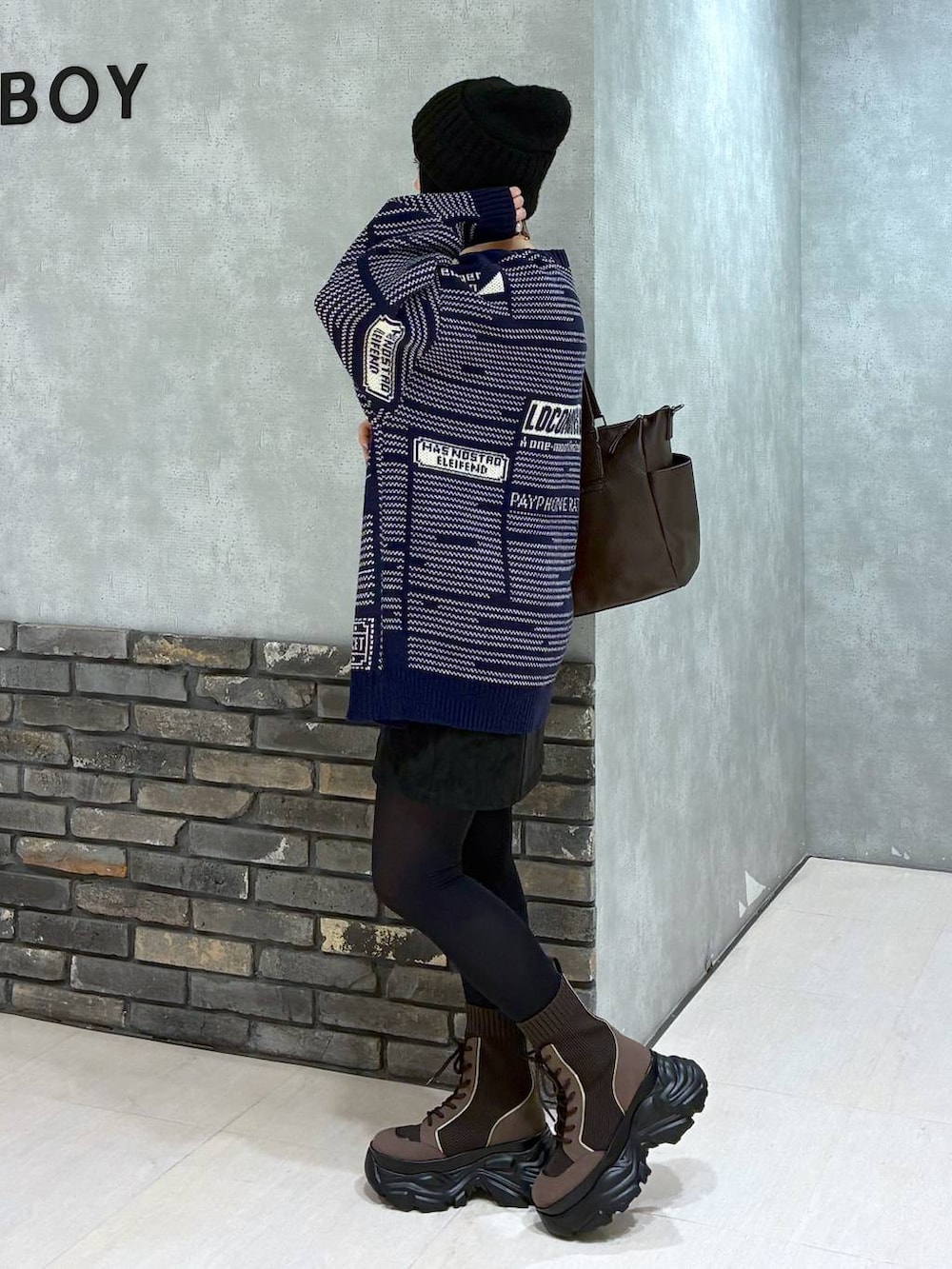 ブラウン系のブーツ、ブラウン系のボストンバッグ、ブラック系のスカートを着用したレディースの冬コーディネートの7枚目の写真