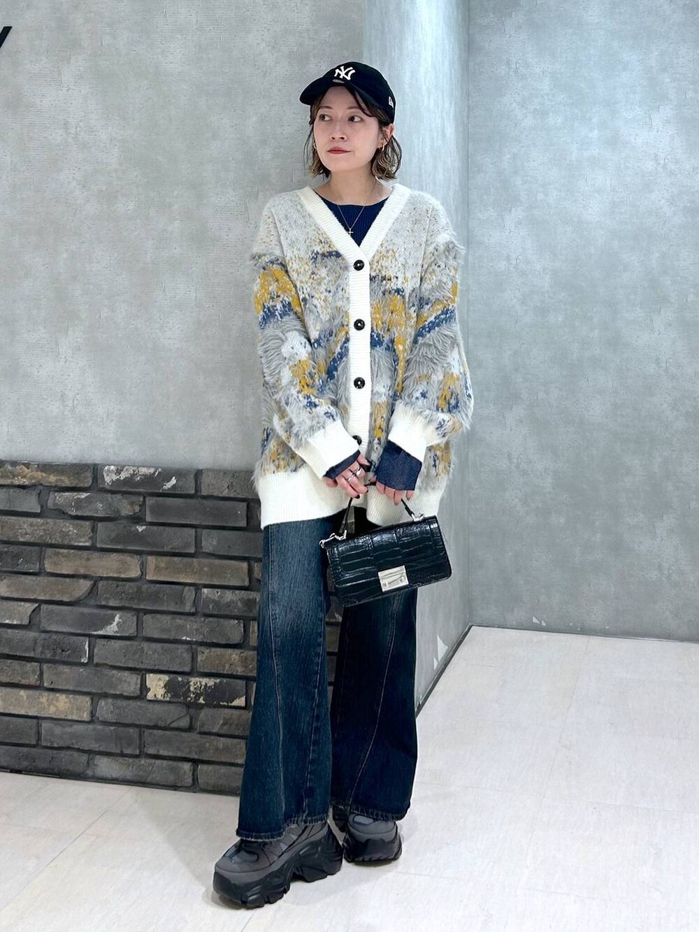 グレー系のスニーカー、ブルー系のデニムパンツ、ブラック系のハンドバッグを着用したレディースの秋コーディネートの2枚目の写真