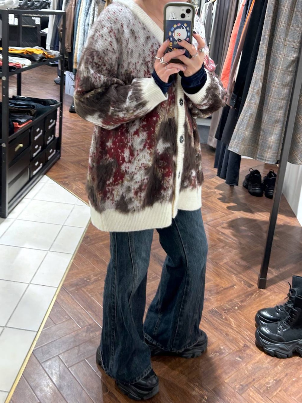 ブラック系のスニーカー、ブルー系のデニムパンツ、ホワイト系のカーディガン/ボレロを着用したレディースの秋コーディネートの4枚目の写真