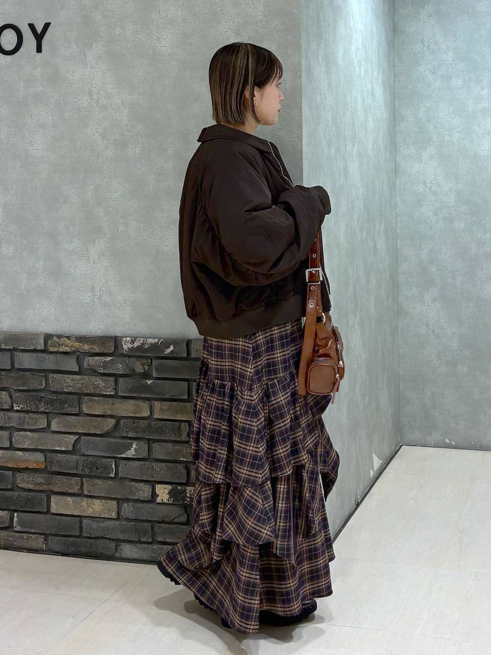 その他のブーツ、ブラウン系のスカート、ブラウン系のショルダーバッグを着用したレディースの冬コーディネートの4枚目の写真