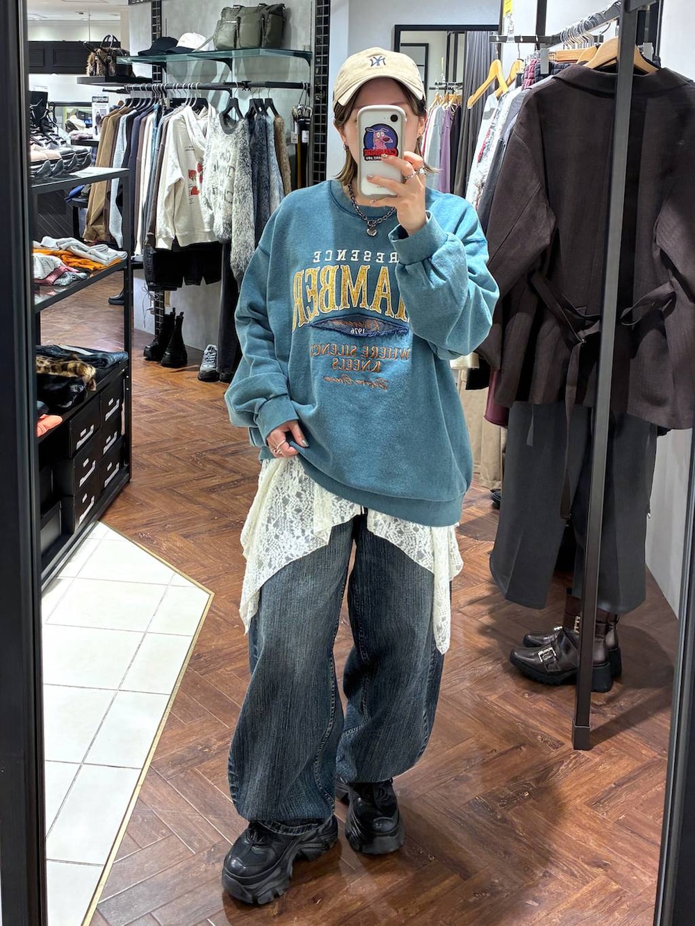 ブラック系のスニーカー、グリーン系のスウェット、ブルー系のデニムパンツを着用したレディースの秋コーディネートの3枚目の写真