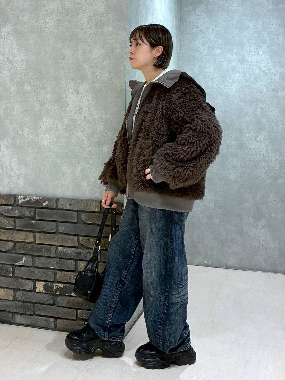 ブラック系のスニーカー、ブラウン系のブルゾン、ブラック系のショルダーバッグを着用したレディースの秋コーディネートの6枚目の写真