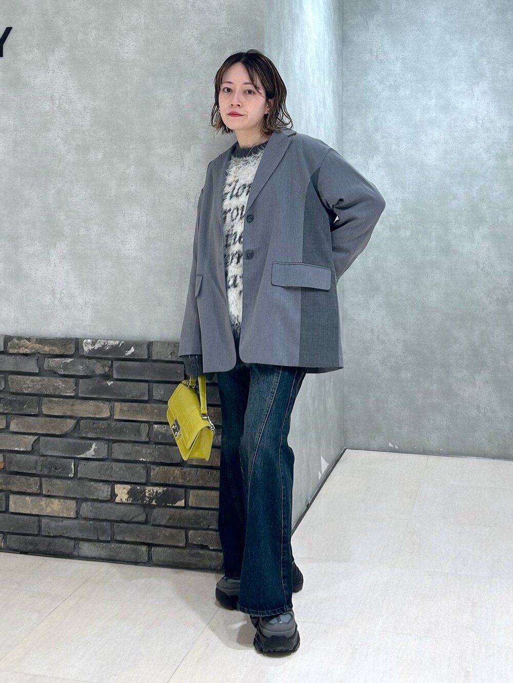 グレー系のスニーカー、ブルー系のデニムパンツ、グレー系のテーラードジャケットを着用したレディースの秋コーディネートの2枚目の写真