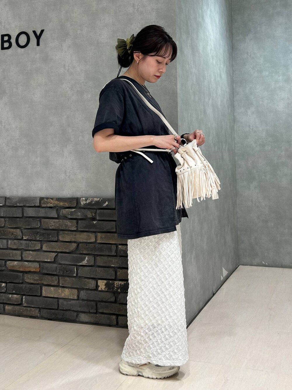 ホワイト系のスカート、ブラック系のTシャツ/カットソー、ホワイト系のショルダーバッグを着用したレディースの夏コーディネートの2枚目の写真