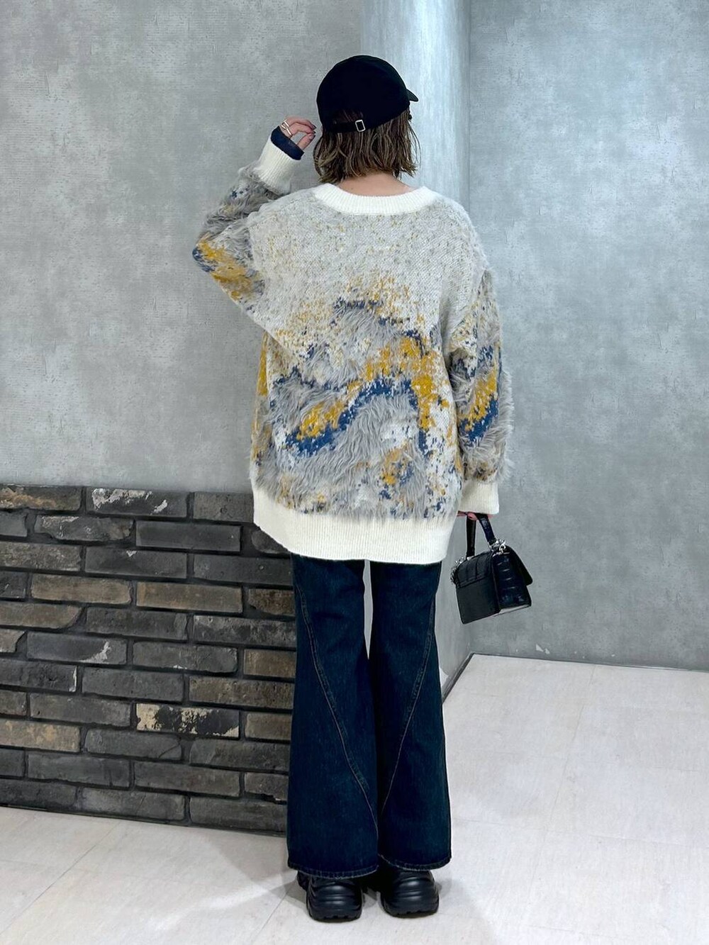 グレー系のスニーカー、ブルー系のデニムパンツ、ブラック系のハンドバッグを着用したレディースの秋コーディネートの5枚目の写真