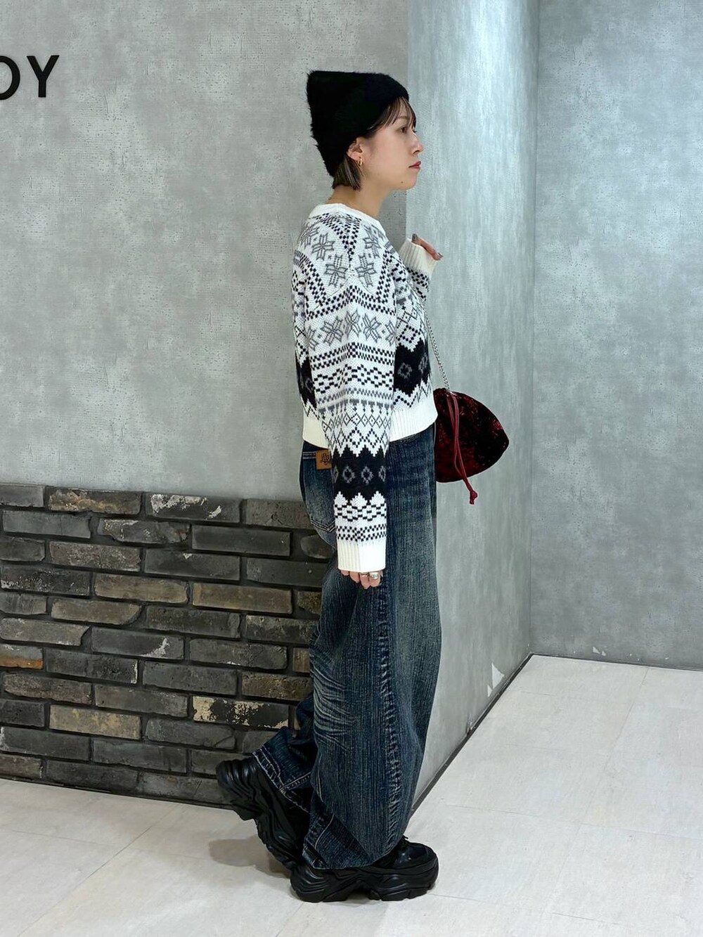 ブラック系のスニーカー、ブルー系のデニムパンツ、レッド系のハンドバッグを着用したレディースの秋コーディネートの2枚目の写真