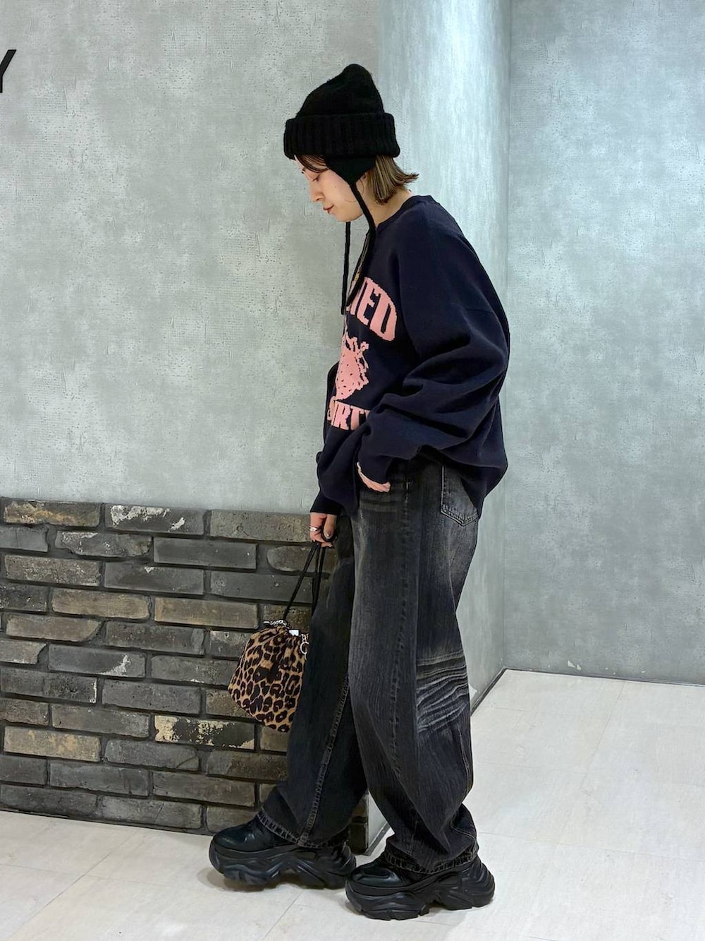 ブラック系のスニーカー、ブルー系のニット/セーター、ブラック系のデニムパンツを着用したレディースの秋コーディネートの6枚目の写真