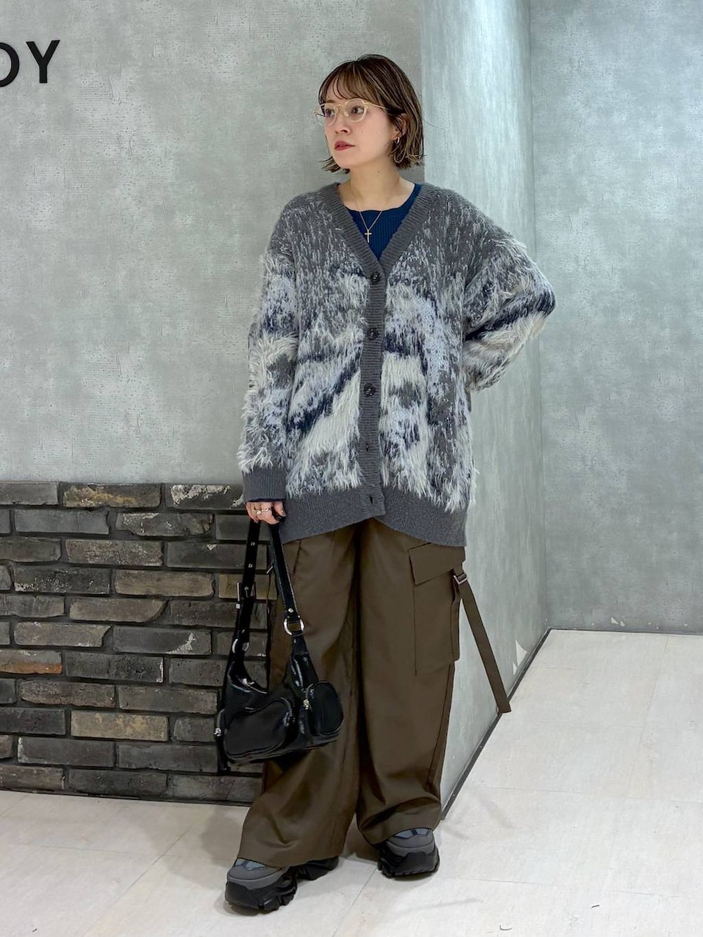 グレー系のスニーカー、ブラウン系のスラックス、グリーン系のニット/セーターを着用したレディースの冬コーディネートの7枚目の写真