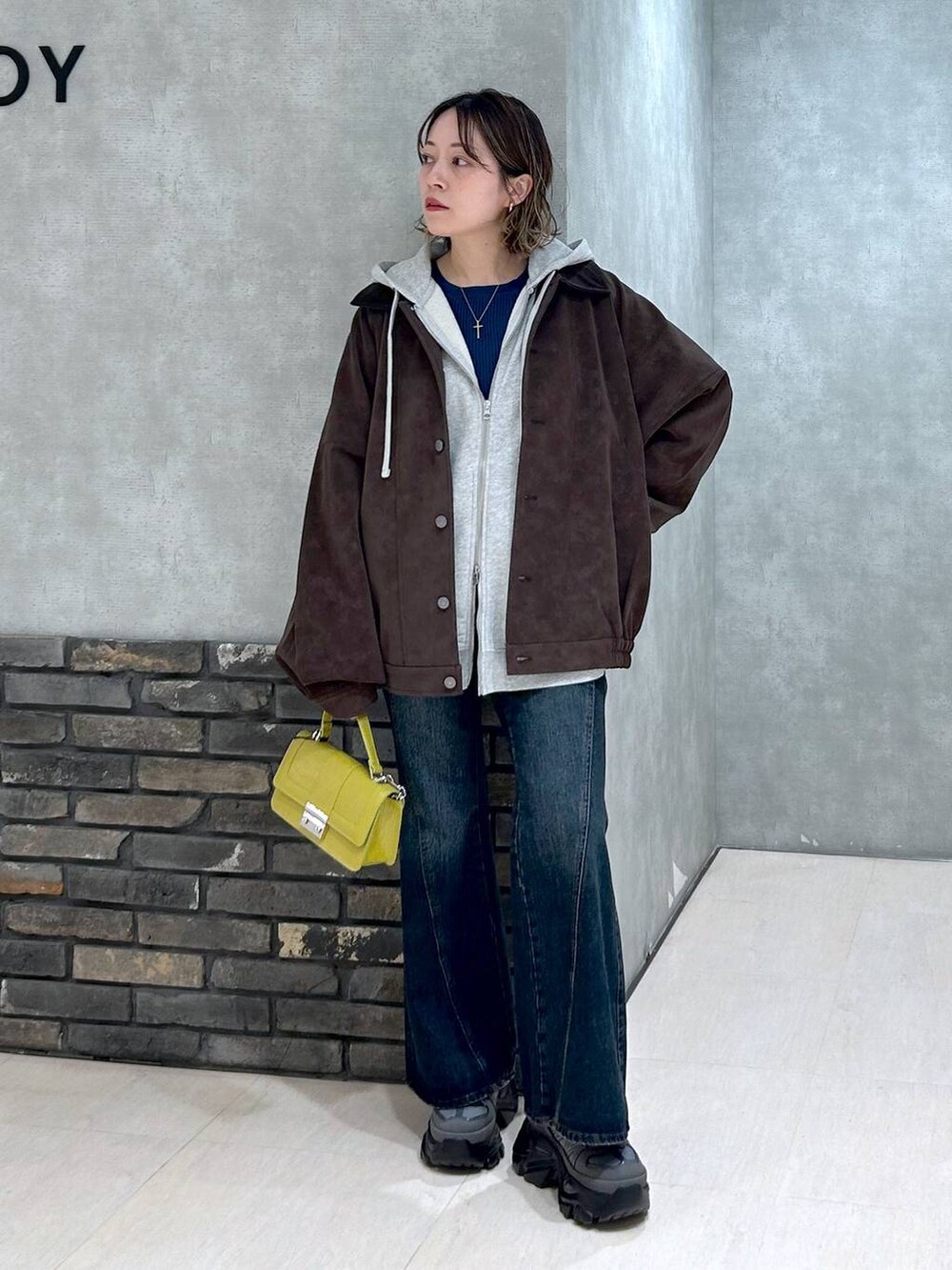 グレー系のスニーカー、ブルー系のデニムパンツ、イエロー系のハンドバッグを着用したレディースの秋コーディネートの8枚目の写真