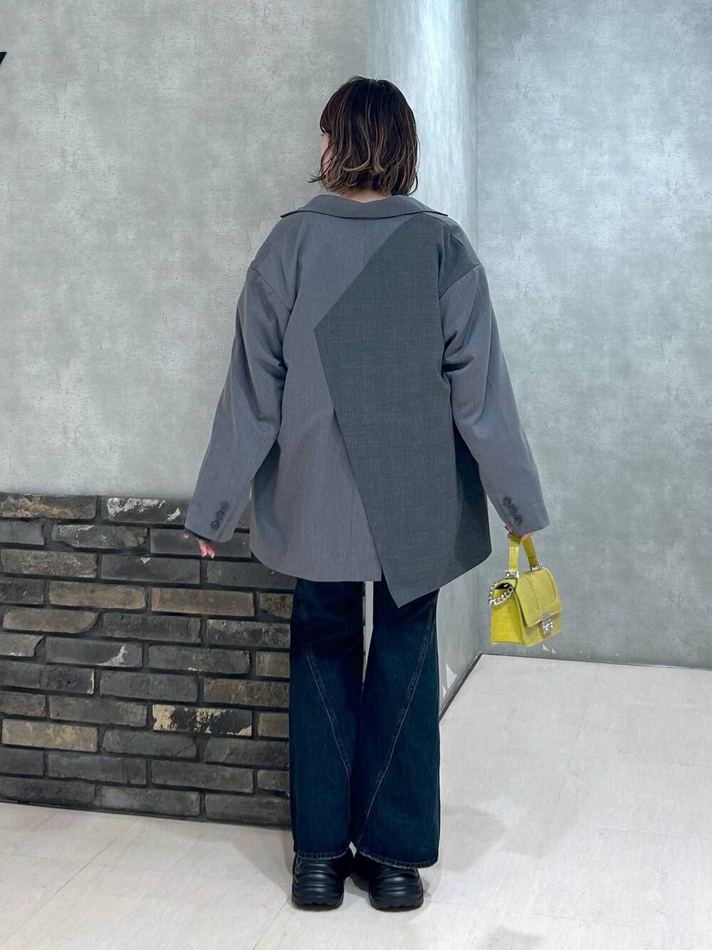 グレー系のスニーカー、ブルー系のデニムパンツ、グレー系のテーラードジャケットを着用したレディースの秋コーディネートの5枚目の写真