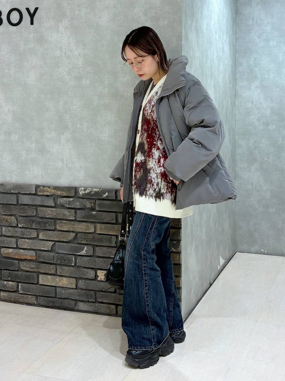 ブラック系のスニーカー、ブルー系のデニムパンツ、グレー系のブルゾンを着用したレディースの冬コーディネートの7枚目の写真