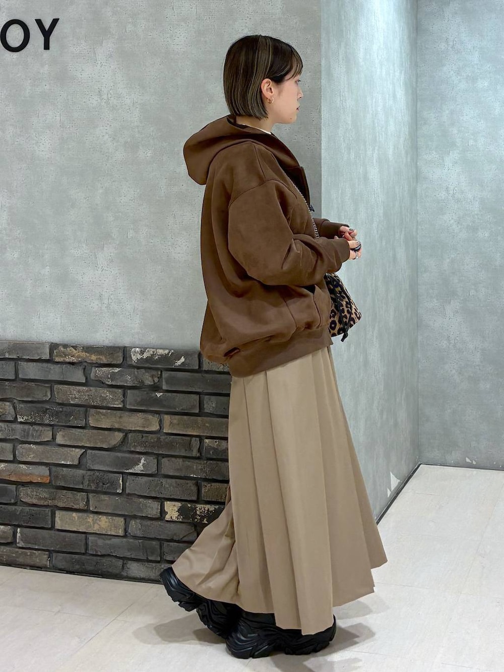 ブラック系のブーツ、ブラウン系のパーカー、ベージュ系のスカートを着用したレディースの冬コーディネートの2枚目の写真