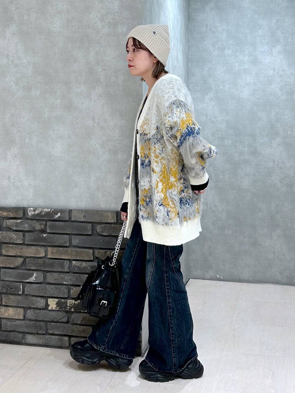 ブラック系のスニーカー、ブルー系のデニムパンツ、ブラック系のショルダーバッグを着用したレディースの秋コーディネートの8枚目の写真