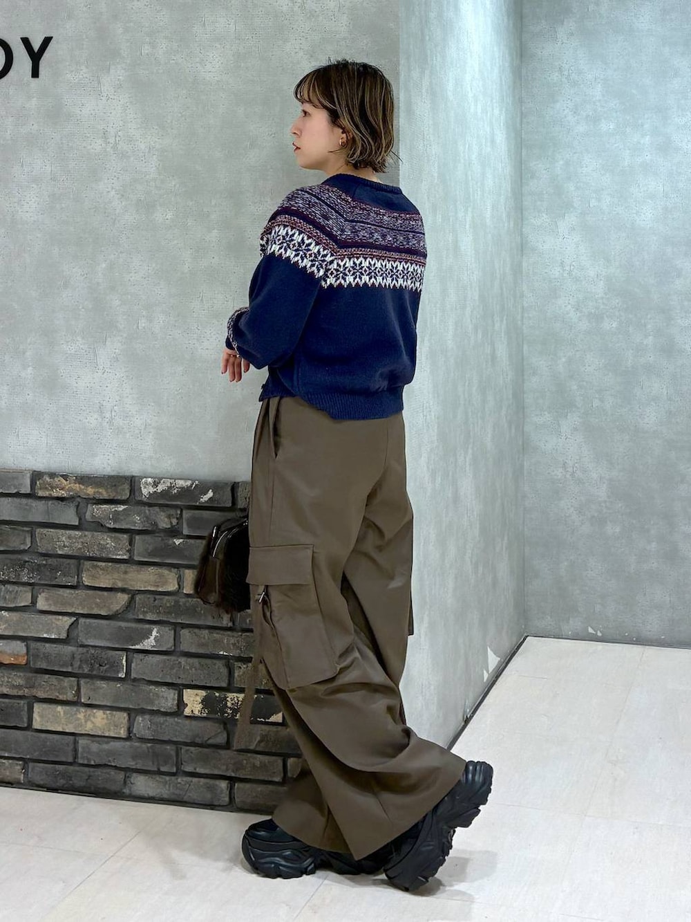 ブラック系のスニーカー、ブラウン系のスラックス、ブラウン系のボストンバッグを着用したレディースの冬コーディネートの5枚目の写真