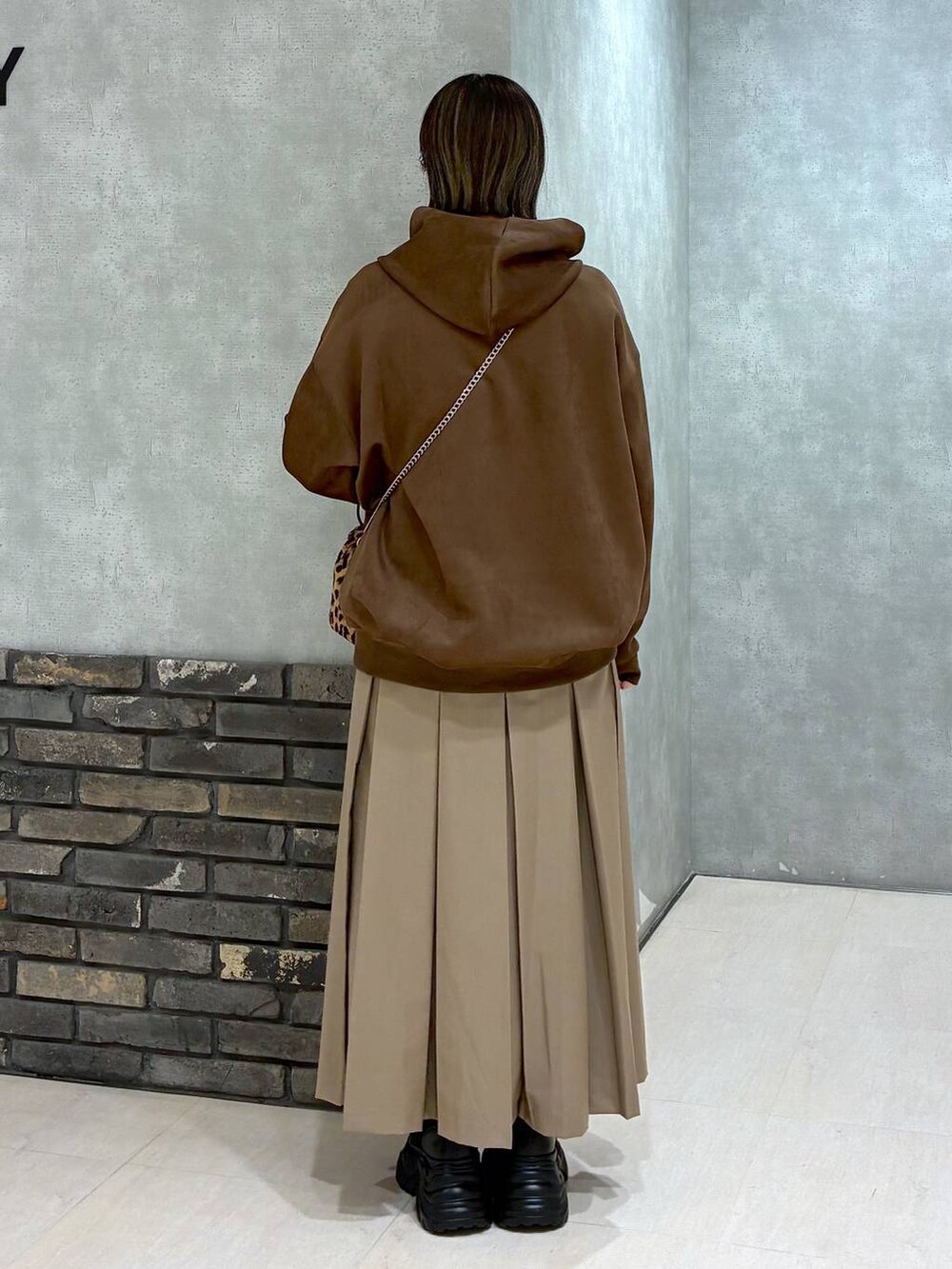 ブラック系のブーツ、ブラウン系のパーカー、ベージュ系のスカートを着用したレディースの冬コーディネートの4枚目の写真