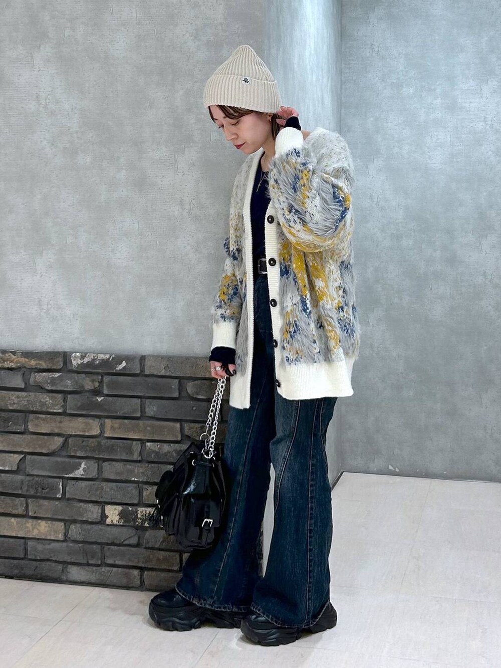 ブラック系のスニーカー、ブルー系のデニムパンツ、ブラック系のショルダーバッグを着用したレディースの秋コーディネートの7枚目の写真