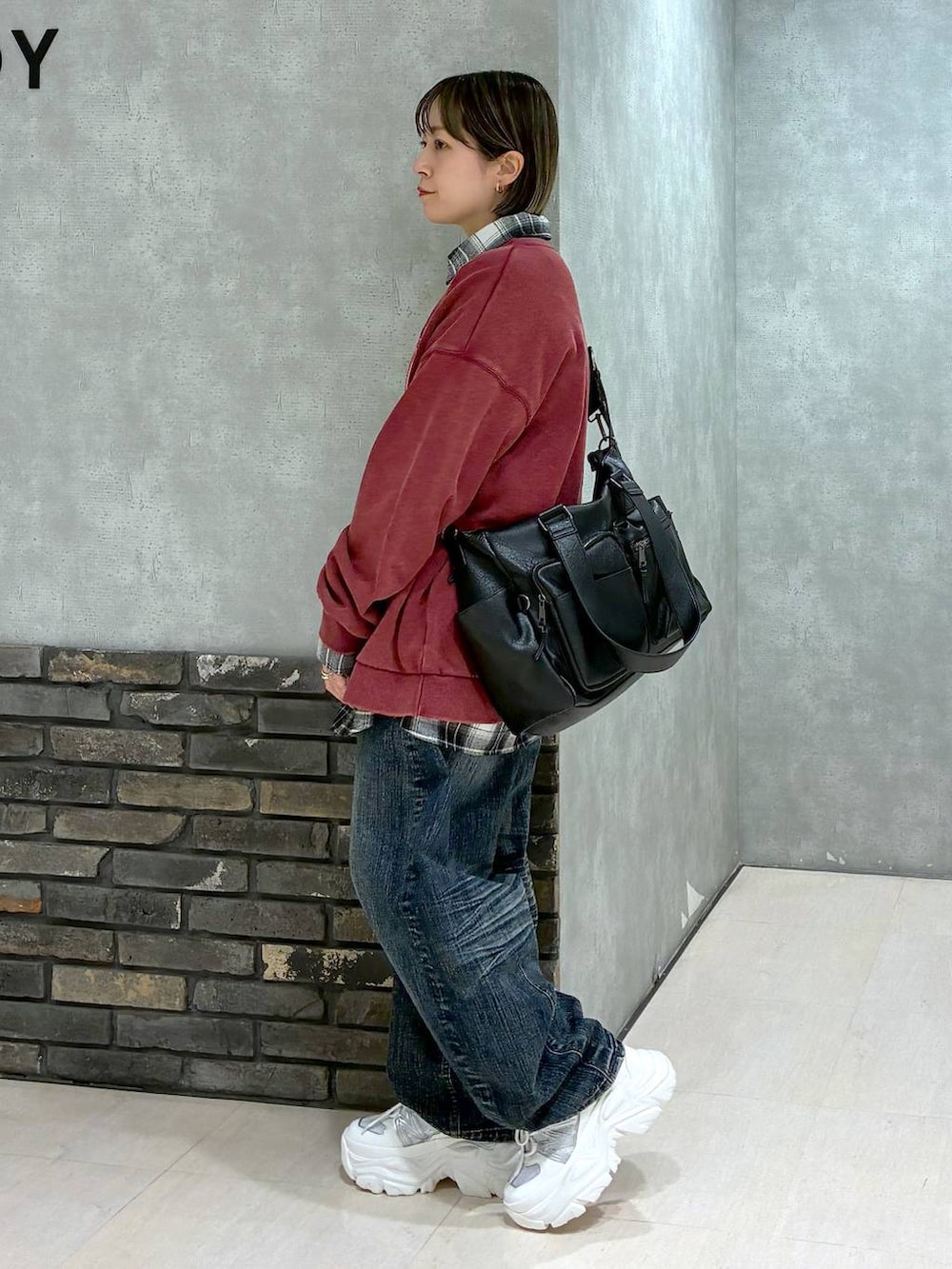 ホワイト系のスニーカー、ブラック系のボストンバッグ、レッド系のスウェットを着用したレディースの冬コーディネートの4枚目の写真