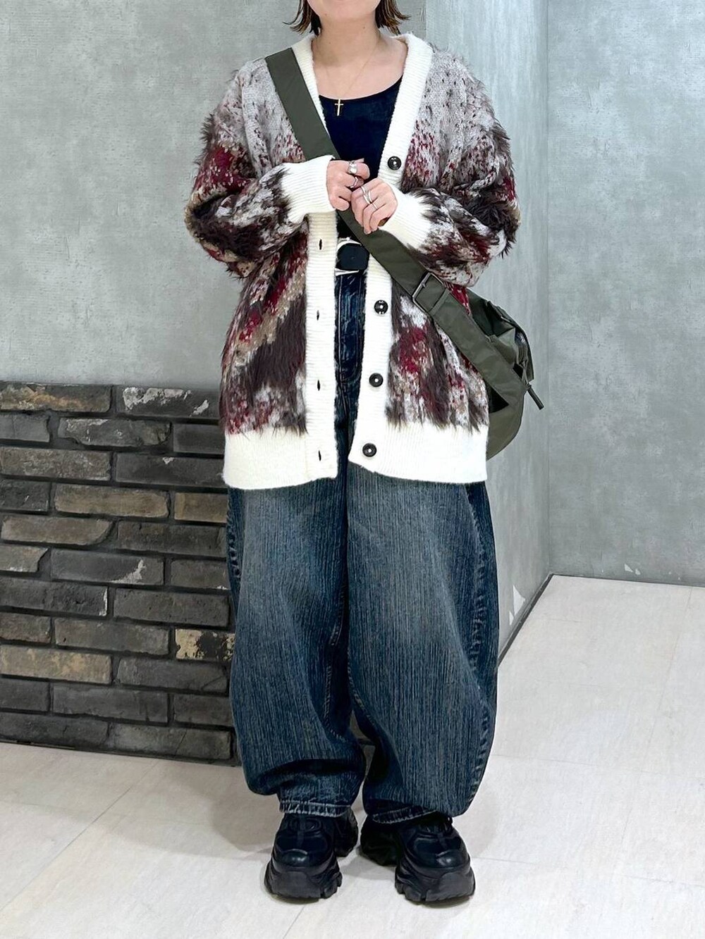 ブラック系のスニーカー、グリーン系のボストンバッグ、ホワイト系のカーディガン/ボレロを着用したレディースの秋コーディネートの6枚目の写真