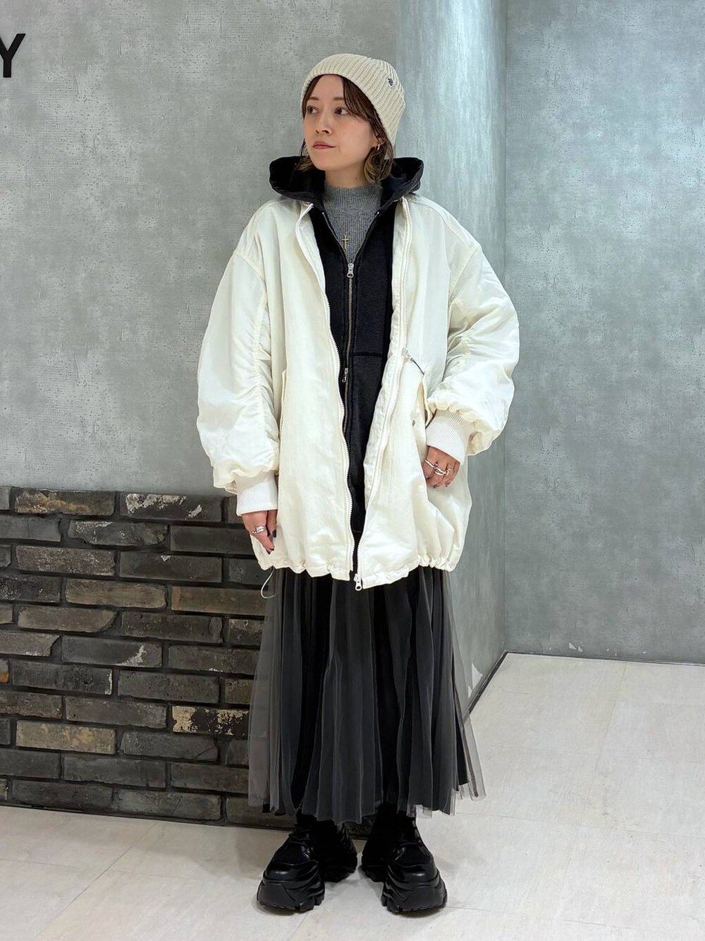 ブラック系のブーツ、ブラック系のパーカー、ホワイト系のブルゾンを着用したレディースの秋コーディネートの2枚目の写真