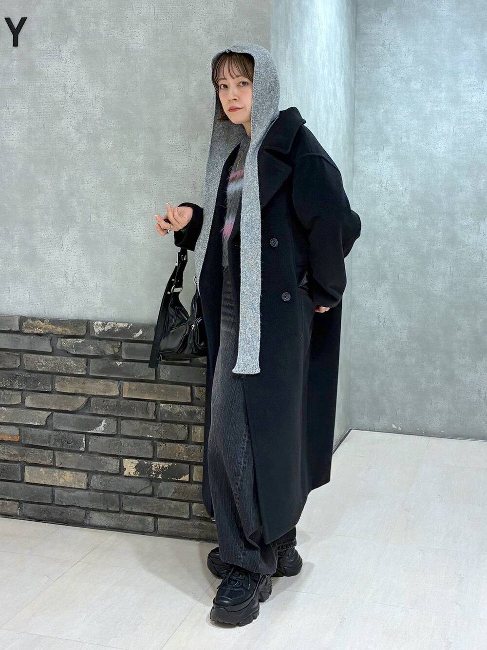 ブラック系のスニーカー、ブラック系のチェスターコート、ブラック系のデニムパンツを着用したレディースの冬コーディネートの5枚目の写真